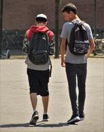 Back view of the guys with backpacks, playing Pokemon Go, outdoors