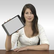 Portrait of the smiling woman, with the Ipad in the hand, at the table, at white background, on the presentation