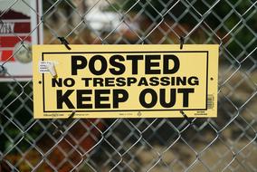 sign posted no trespassing keep out on a wire fence on a blurred background