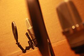 Close-up of the beautiful, shiny microphone, for recording, near the brown wall
