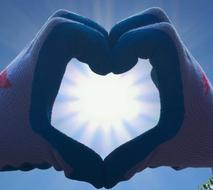 Charity symbol, sun shining through heart gesture
