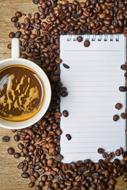 blank sheet of paper in coffee beans near a cup of coffee