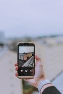 Person with the wrist watch, taking a photo of the buildings, on the smartphone