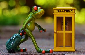 Cute green ceramic frog with luggage and yellow telephone booth