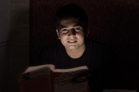 guy reading a book in the dark