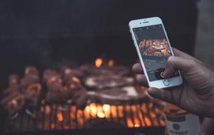 man photographs grill on smartphone