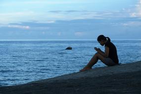 Silhouette of a girl on the beautiful seaside with blue water