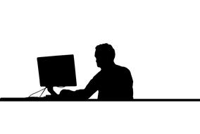 black silhouette of a man at the computer