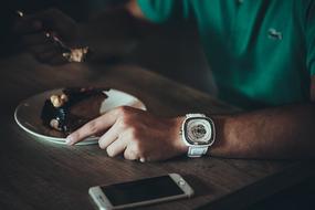 wristwatch on hand of man eating Dessert