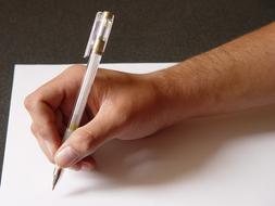 Person, with the pen in hand, writing on the white paper