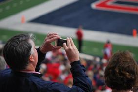 man with an iPhone on the podium of the stadium