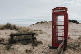 red phone booth on the beach on a cloudy day