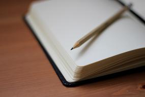Close-up of the beautiful, wooden pencil, on the pages of the notebook, on the wooden desk