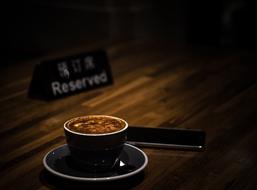 Coffee in dark cup and smartphone on table