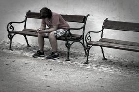 teenager with phone on the bench near the wall