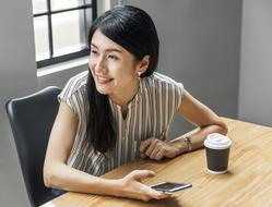 a girl with a smartphone in her hand sits at the table