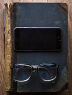 glasses and smart phone on an old book