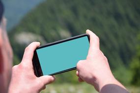 a smartphone with a green screen in the hands of a man