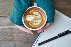 a cup of cappuccino with beautiful foam in the hands of a girl