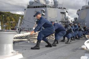 Sailors pulling a rope on the ship, in teamwork