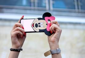 Mobile phone with cute case in stretched female hands