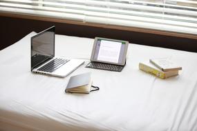 Laptop, tablet, notebook and colorful books, on the white workspace