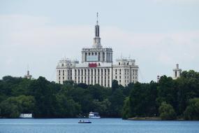 Beautiful palace, among the green trees, on the shore of the lake in Bucharest, Romania