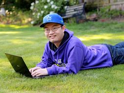 Portrait of a man with the glass, using laptop, on the green and yellow grass