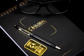 black pen and glasses on notepad