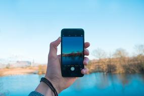 river landscape on smartphone screen in hand on blurred background