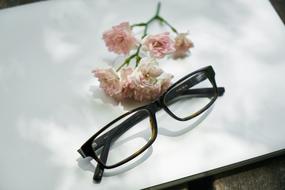 Glasses and beautiful, pink and white flowers, on the white laptop, in light