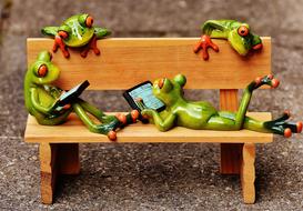 figurines of frogs on a wooden bench