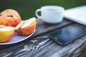 cup of coffee, smartphone and garden apples on a wooden table