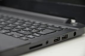 Close-up of the grey and black laptop, with white numbers and signs, on the white table