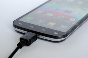 Black and grey smartphone, charging with the black cable