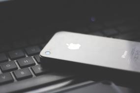 Close-up of the shiny Iphone, on the black keyboard, in light and shadow