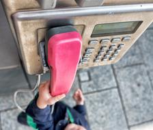 child near a street phone with a pink tube