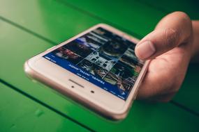 mobile phone in hand on green surface background