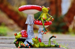 ceramic figurine from frogs near fly agarics on a blurred background
