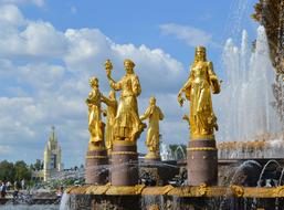 Shiny, gold Peoples' Friendship Fountain in Moscow, Russia, under the blue sky with clouds