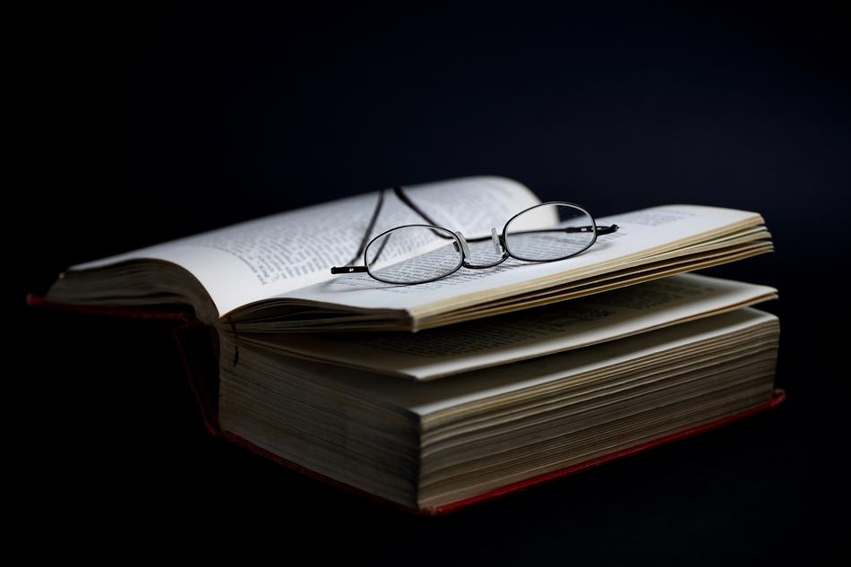 Beautiful glasses on the open book at black background