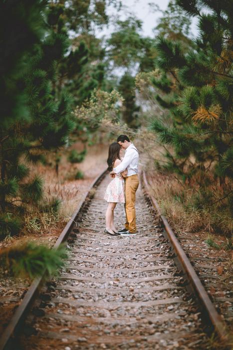 couple in love kissing on the train tracks among the greenery