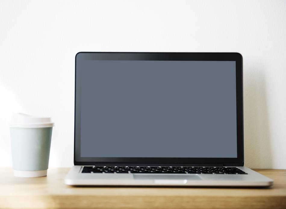 Beautiful laptop and blue and white paper cup on the wooden table