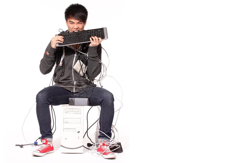 man biting the keyboard while sitting on a chair