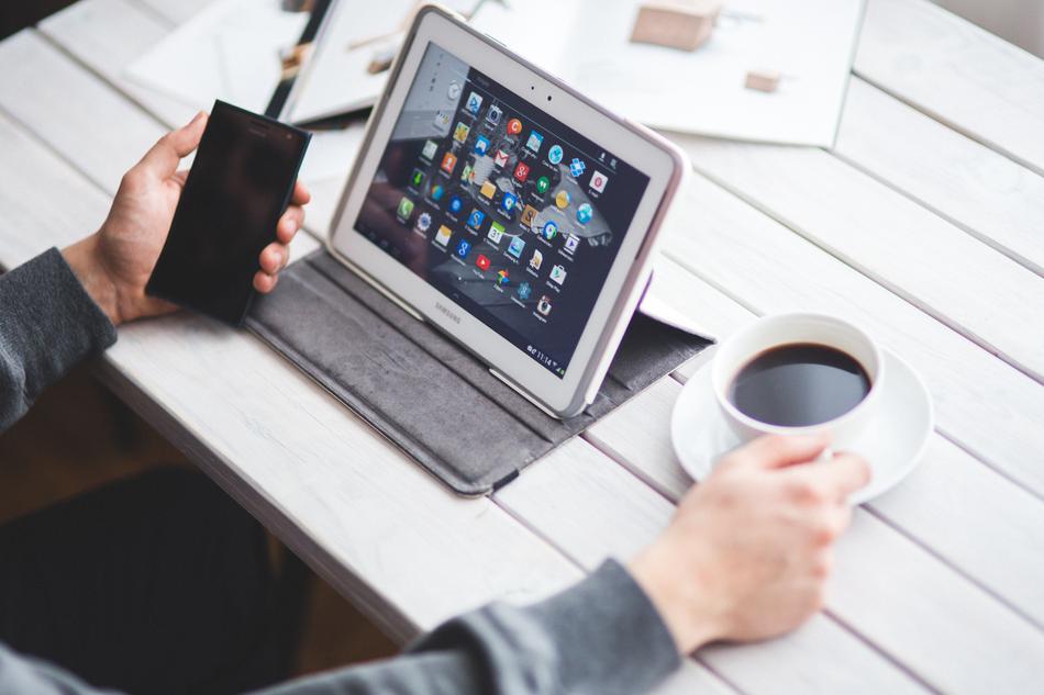 A man sitting at a tablet with a cup of coffee