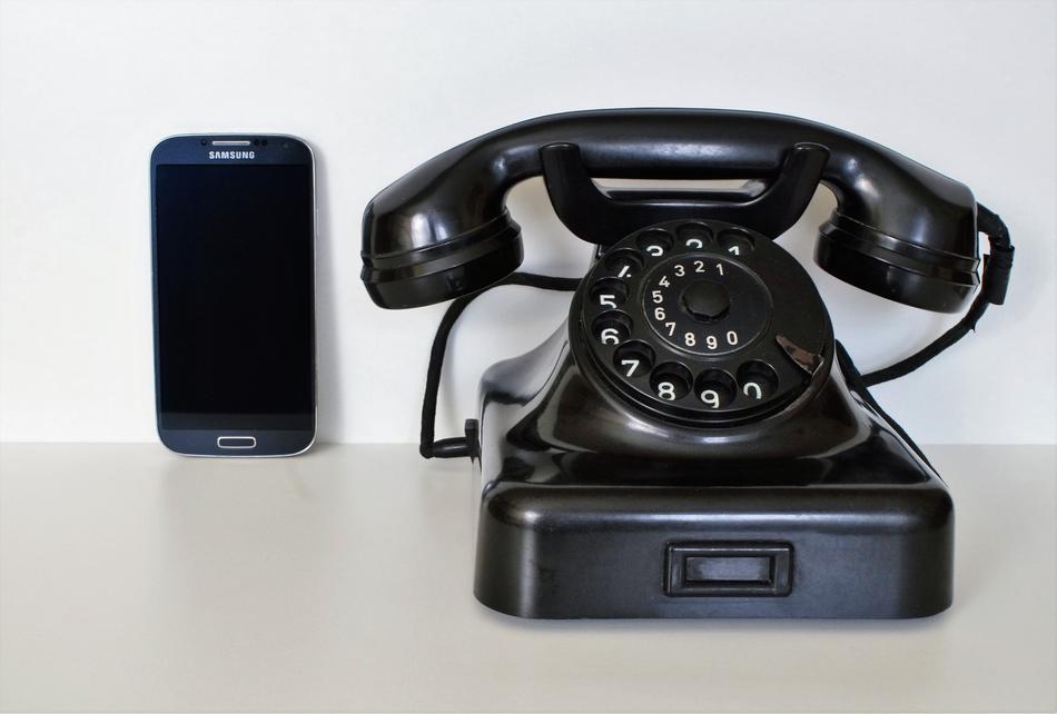 Beautiful, retro black phone and Samsung smartphone near the white wall