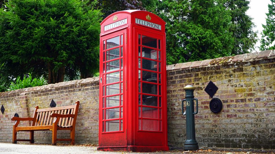 red telephone booth near brick wall on the streets of england