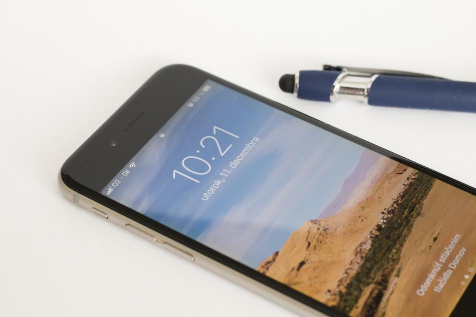 Black and metallic Iphone, with the colorful screen, near the blue and metallic pen, on the O2 Slovakia