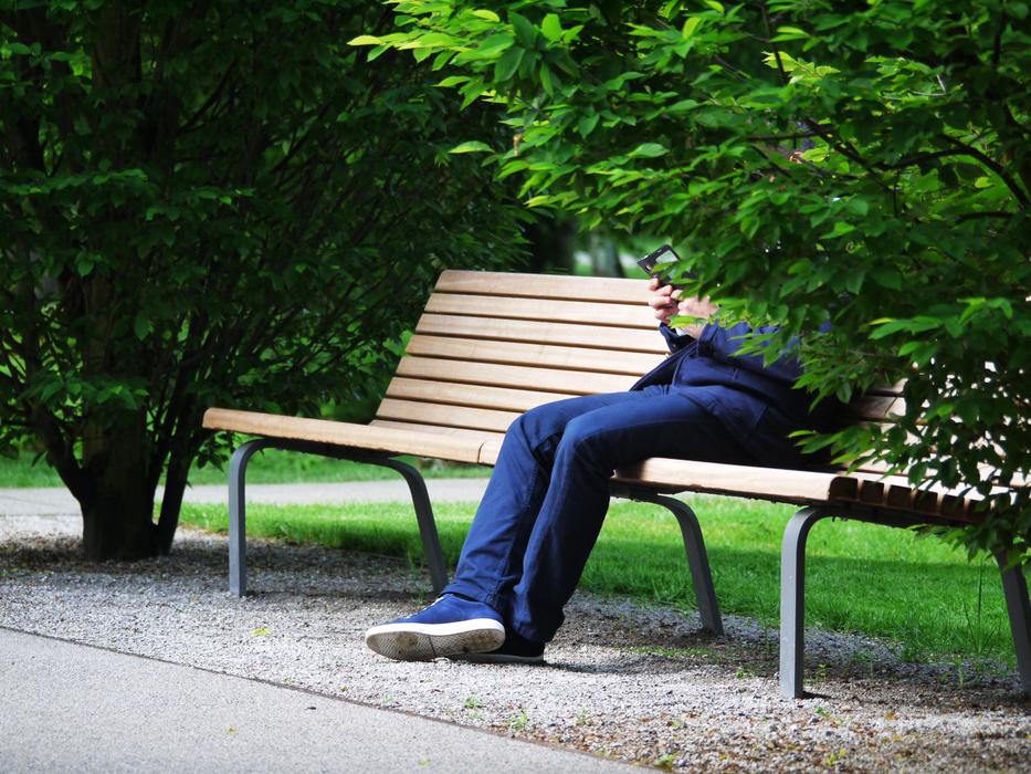 man with smartphone in the park on the bench