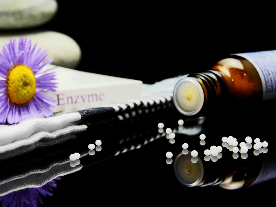 Globuli with the bottle, near the book, with the beautiful, purple and yellow flower, with the reflections